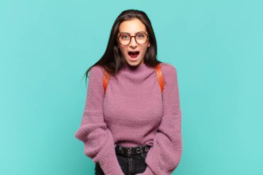 Genç ve güzel bir kadın korkmuş ve şok olmuş hissediyor, ağzı açık bir şekilde şaşkınlık içinde. öğrenci konsepti