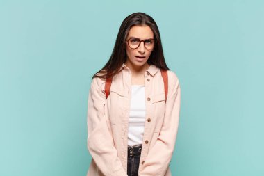 young pretty woman feeling puzzled and confused, with a dumb, stunned expression looking at something unexpected. student concept