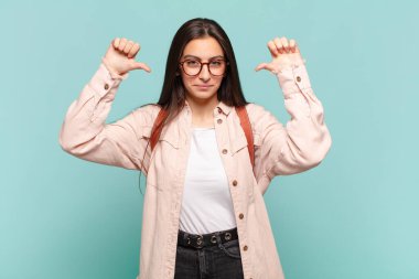 Genç, güzel bir kadın gururlu, kibirli ve kendinden emin, tatmin olmuş ve başarılı görünüyor, kendini işaret ediyor. öğrenci konsepti