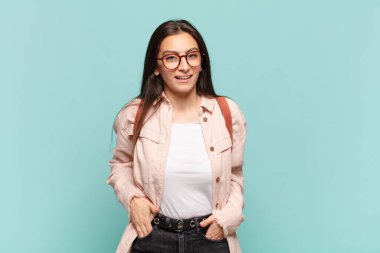 Genç, güzel bir kadın neşeli ve tesadüfen gülümsüyor. Olumlu, mutlu, kendinden emin ve rahat bir ifadeyle. öğrenci konsepti