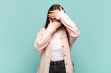 Genç ve güzel bir kadın iki eliyle kameraya hayır diyerek yüzünü kapatıyor! Fotoğrafları reddetmek ya da yasaklamak. öğrenci konsepti