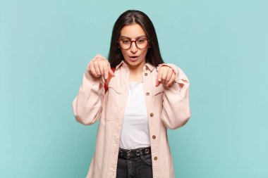 Genç, güzel bir kadın şok olmuş, ağzı açık ve şaşırmış, inançsızlık ve şaşkınlık içinde bakıyor ve onu işaret ediyor. öğrenci konsepti
