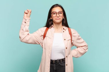 Genç ve güzel bir kadın ciddi, güçlü ve asi hissediyor, yumruğunu kaldırıyor, protesto ediyor ya da devrim için savaşıyor. öğrenci konsepti