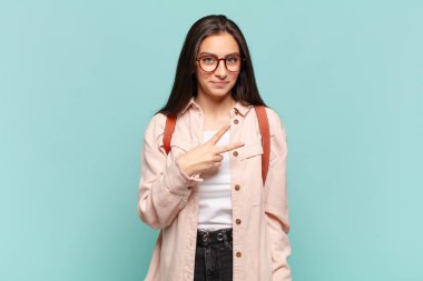 Genç, güzel bir kadın kendini mutlu, pozitif ve başarılı hissediyor. Elleriyle göğsüne V şekli yapıyor. Zafer ya da huzur veriyor. öğrenci konsepti