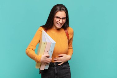 Genç ve güzel bir kadın komik bir şakaya yüksek sesle gülüyor, mutlu ve neşeli hissediyor, eğleniyor. öğrenci konsepti