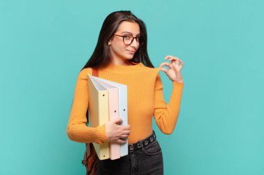 Genç ve güzel bir kadın kibirli, başarılı, pozitif ve gururlu görünüyor, kendini işaret ediyor. öğrenci konsepti