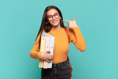 Genç, güzel bir kadın, kendine güvenerek gülümsüyor. Geniş bir gülümseme, pozitif, rahat, tatmin olmuş bir tavır sergiliyor. öğrenci konsepti