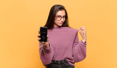 Genç ve güzel bir kadın kibirli, başarılı, pozitif ve gururlu görünüyor, kendini işaret ediyor. telefon ekranı kavramı