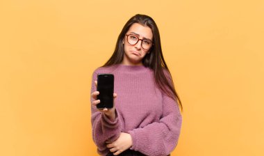 Genç, güzel bir kadın üzgün ve mızmızlanıyor. Mutsuz bir bakışı var. Olumsuz ve hayal kırıklığına uğramış bir tavırla ağlıyor. telefon ekranı kavramı
