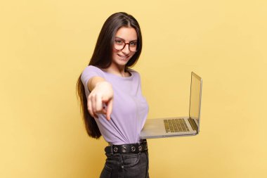 Genç ve güzel bir kadın kameraya bakıyor. Tatmin olmuş, kendinden emin, dostane bir gülümsemeyle. Seni seçiyor. dizüstü bilgisayar