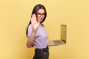 Genç ve güzel bir kadın ciddi, sert, hoşnutsuz ve kızgın görünüyor. dizüstü bilgisayar