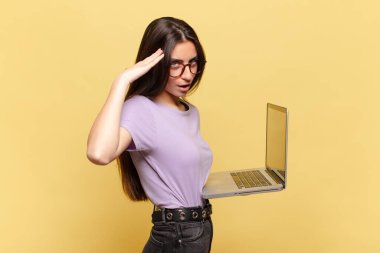 Genç, güzel bir kadın mutlu, şaşkın ve şaşırmış görünüyor, gülümsüyor ve inanılmaz ve inanılmaz iyi haberleri fark ediyor. dizüstü bilgisayar