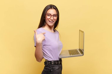 Genç, güzel bir kadın mutlu, şaşırmış ve gururlu hissediyor. Heyecanlı ve şaşkın bir bakışla kendini işaret ediyor. dizüstü bilgisayar