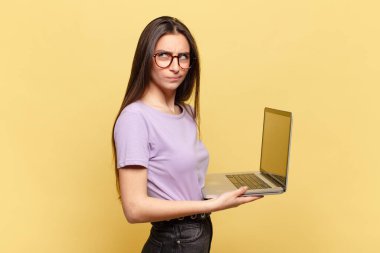 Genç, güzel bir kadın üzgün, üzgün ya da kızgın. Olumsuz bir tavırla yan yana bakıyor, anlaşmazlık içinde kaşlarını çatıyor. dizüstü bilgisayar