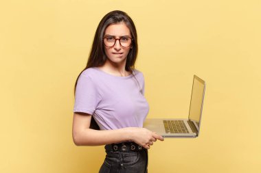 Kafası karışmış ve kafası karışmış genç bir kadın gergin bir hareketle dudağını ısırıyor, sorunun cevabını bilmiyor. dizüstü bilgisayar