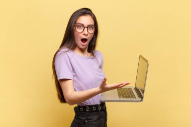 Genç ve güzel bir kadın şok olmuş ve şaşırmış, endişeli ve paniklemiş hissediyor, stresli ve dehşete kapılmış bir bakışla. dizüstü bilgisayar