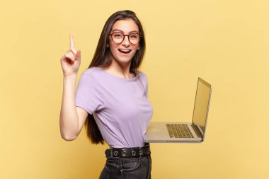 Genç ve güzel bir kadın bir fikri fark ettikten sonra mutlu ve heyecanlı bir dahi gibi hissediyor, neşeli bir şekilde parmağını kaldırıyor, eureka! dizüstü bilgisayar