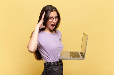 Genç ve güzel bir kadın ellerini havaya kaldırıp bağırıyor. Öfkeli, sinirli, stresli ve üzgün hissediyor. dizüstü bilgisayar