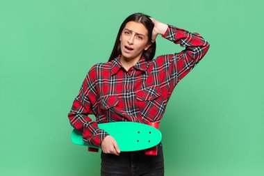 Genç, güzel bir kadın kendini stresli, endişeli, endişeli ya da korkmuş hissediyor. Elleri başının üstünde, hatayla panikliyor. kaykay konsepti