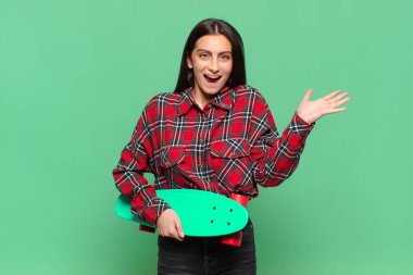 Genç, güzel bir kadın mutlu, heyecanlı, şaşırmış ya da şok olmuş hissediyor. İnanılmaz bir şeye gülümsüyor ve hayrete düşüyor. kaykay konsepti