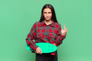 Genç ve güzel bir kadın kızgın, sinirli, isyankar ve agresif hissediyor. Orta parmağını hareket ettiriyor, karşı koyuyor. kaykay konsepti