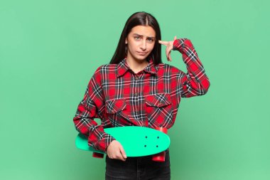 Genç, güzel bir kadın kafası karışık ve şaşkın hissediyor. Deli, deli ya da aklını kaçırmış olduğunu gösteriyor. kaykay konsepti