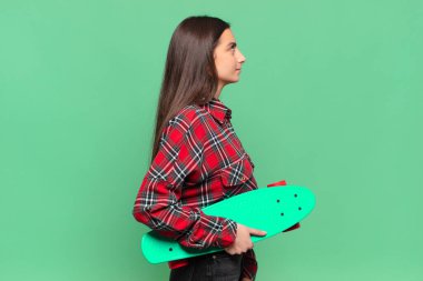 Profil görünümünde genç ve güzel bir kadın uzayı kopyalamaya çalışıyor. Düşünüyor, hayal ediyor ya da hayal kuruyor. kaykay konsepti