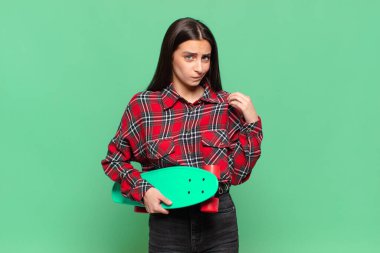 Genç ve güzel bir kadın kibirli, başarılı, pozitif ve gururlu görünüyor, kendini işaret ediyor. kaykay konsepti