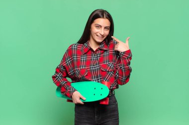 Genç, güzel bir kadın, kendine güvenerek gülümsüyor. Geniş bir gülümseme, pozitif, rahat, tatmin olmuş bir tavır sergiliyor. kaykay konsepti