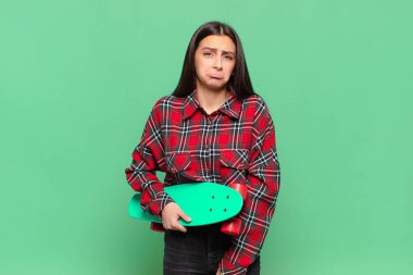 Genç, güzel bir kadın üzgün ve mızmızlanıyor. Mutsuz bir bakışı var. Olumsuz ve hayal kırıklığına uğramış bir tavırla ağlıyor. kaykay konsepti