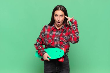 Genç, güzel bir kadın şaşırmış, ağzı açık, şok olmuş, yeni bir düşünce, fikir ya da konsept keşfediyor. kaykay konsepti