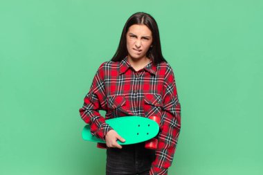 Kafası karışmış ve kafası karışmış genç bir kadın gergin bir hareketle dudağını ısırıyor, sorunun cevabını bilmiyor. kaykay konsepti