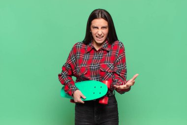 Genç ve güzel bir kadın sinirli, sinirli ve hayal kırıklığına uğramış görünüyor. Ya da senin neyin var? kaykay konsepti