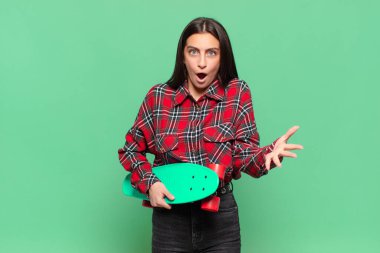 Genç ve güzel bir kadın ağzı açık ve şaşırmış, şok olmuş ve hayrete düşmüş inanılmaz bir sürprizle. kaykay konsepti