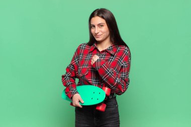 Genç ve güzel bir kadın mutlu, pozitif ve başarılı hisseder, bir meydan okumayla karşılaştığında ya da iyi sonuçları kutladığında motive olur. kaykay konsepti