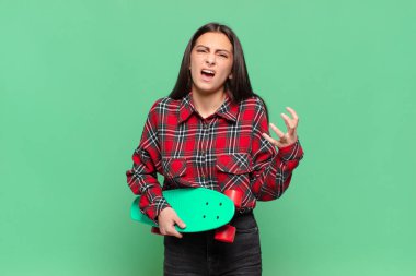 Genç ve güzel bir kadın umutsuz ve hayal kırıklığına uğramış görünüyor, stresli, mutsuz ve sinirli, bağırıyor ve çığlık atıyor. kaykay konsepti