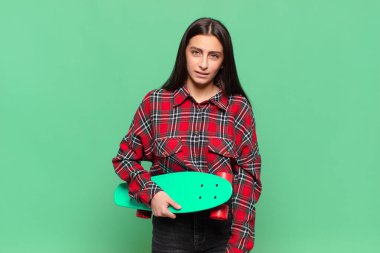 young pretty woman feeling puzzled and confused, with a dumb, stunned expression looking at something unexpected. skate board concept