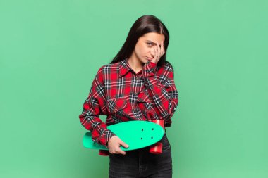 Genç ve güzel bir kadın yorgun, sıkıcı ve can sıkıcı bir işten sonra sıkılmış, hayal kırıklığına uğramış ve uykulu hissediyor, el ele tutuşarak. kaykay konsepti