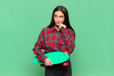 Genç, güzel bir kadın düşünüyor, kuşkulu ve şaşkın hissediyor, farklı seçeneklerle, hangi kararı vereceğini merak ediyor. kaykay konsepti