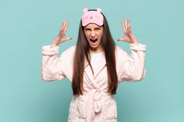 Genç ve güzel bir kadın ellerini havaya kaldırıp bağırıyor. Öfkeli, sinirli, stresli ve üzgün hissediyor. Pijama giyip uyanmak