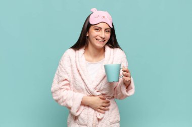 Genç ve güzel bir kadın komik bir şakaya yüksek sesle gülüyor, mutlu ve neşeli hissediyor, eğleniyor. Pijama giyip uyanmak