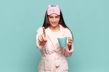 Genç ve güzel bir kadın gururla gülümsüyor ve gururla bir numaralı pozunu veriyor, bir lider gibi hissediyor. Pijama giyip uyanmak