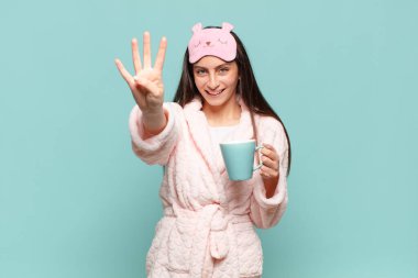 Genç, güzel bir bayan gülümsüyor ve arkadaş canlısı görünüyor. Dört ya da dört numarayı gösteriyor. Elleri önde ve geri sayıyor. Pijama giyip uyanmak