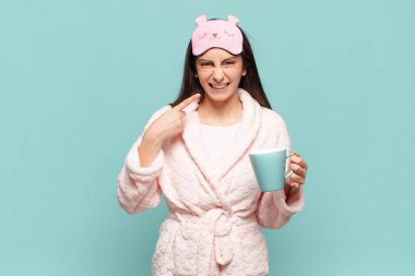 Genç, güzel bir kadın, kendine güvenerek gülümsüyor. Geniş bir gülümseme, pozitif, rahat, tatmin olmuş bir tavır sergiliyor. Pijama giyip uyanmak