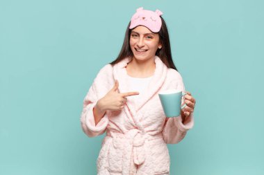 Genç ve güzel bir kadın heyecanlı ve şaşırmış görünüyor. Yana ve yukarı doğru uzayı işaret ediyor. Pijama giyip uyanmak