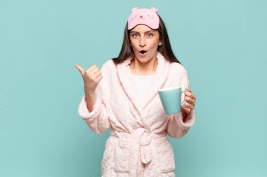 Genç ve güzel bir kadın inançsızlıktan şaşkın şaşkın bakıyor, yan taraftaki objeyi işaret ediyor ve 