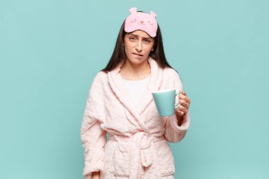 Kafası karışmış ve kafası karışmış genç bir kadın gergin bir hareketle dudağını ısırıyor, sorunun cevabını bilmiyor. Pijama giyip uyanmak