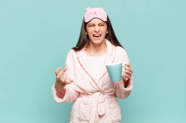 Genç ve güzel bir kadın umutsuz ve hayal kırıklığına uğramış görünüyor, stresli, mutsuz ve sinirli, bağırıyor ve çığlık atıyor. Pijama giyip uyanmak