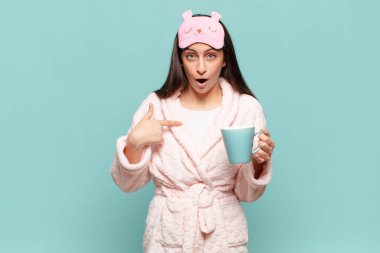 Şok olmuş ve ağzı açık, kendini gösteren genç ve güzel bir kadın. Pijama giyip uyanmak