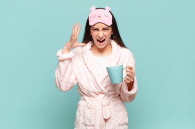 Genç ve güzel bir kadın ellerini havaya kaldırıp bağırıyor. Öfkeli, sinirli, stresli ve üzgün hissediyor. Pijama giyip uyanmak